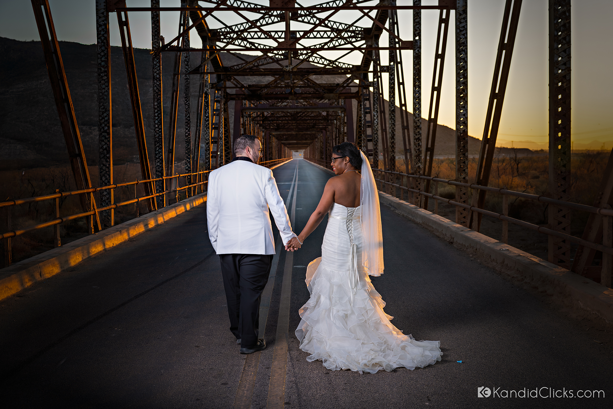 Bride and groom holding hands and walking away on a rustic bridge in Arizona.