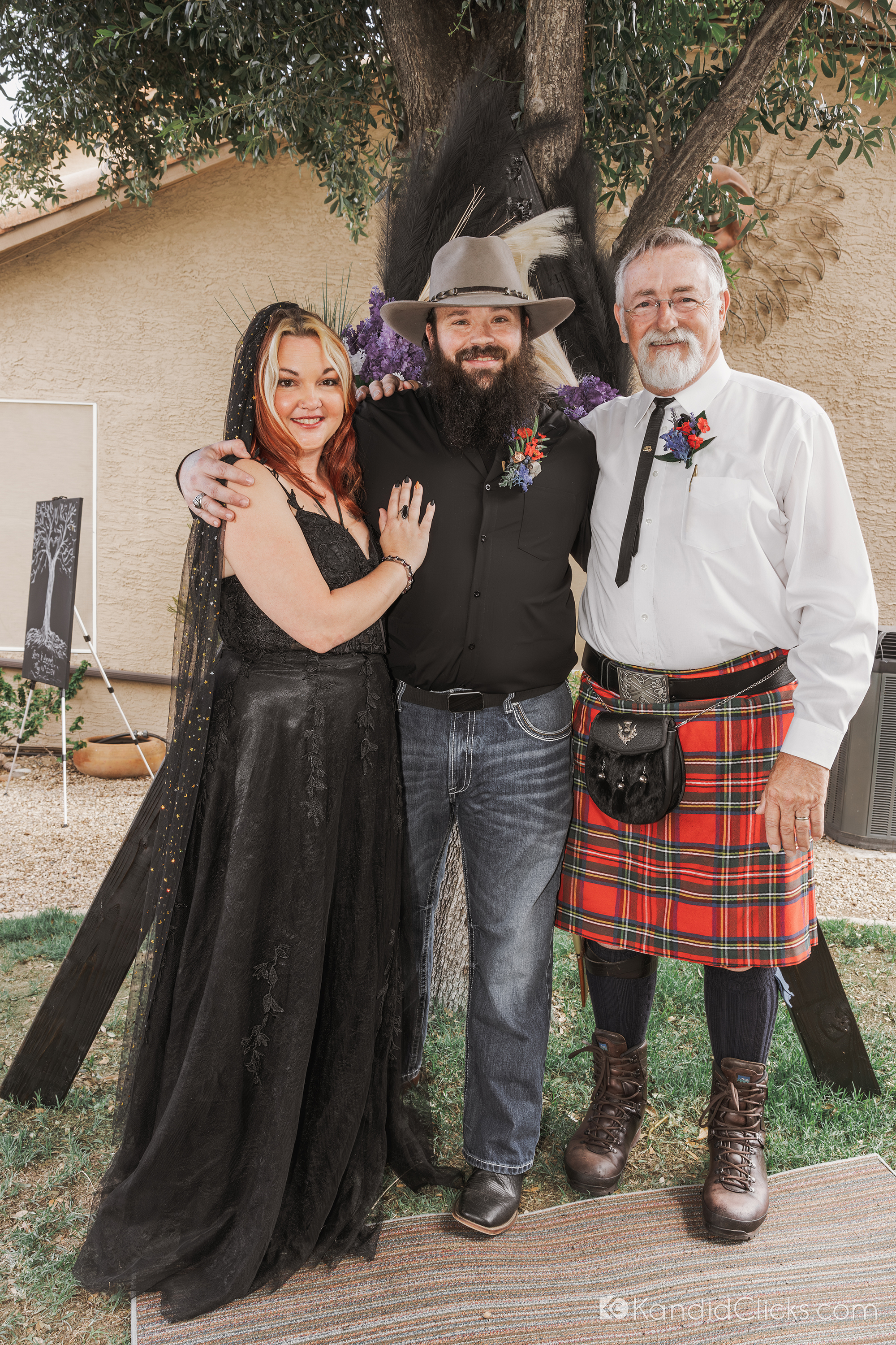 Bride and groom posing with officiant in backyard Arizona wedding portrait.