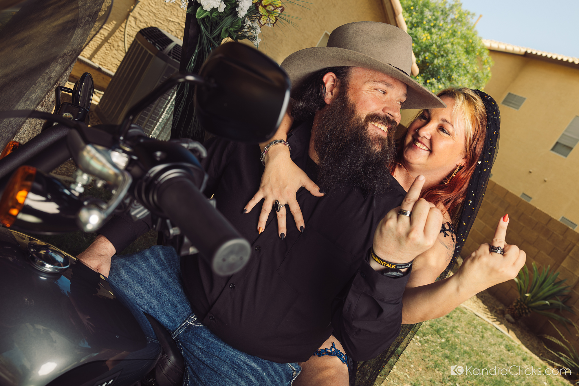 Bride and groom flash wedding rings with attitude on a motorcycle.