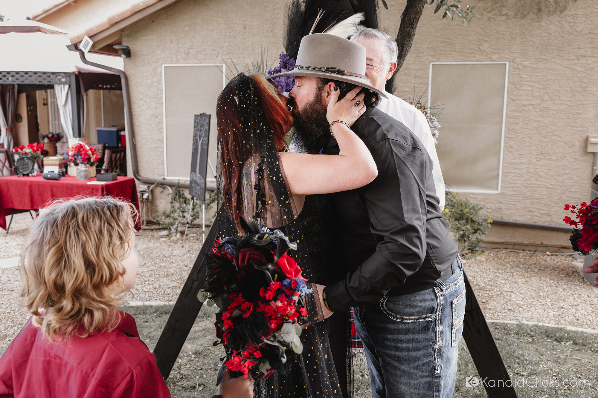 Bride and groom share their first kiss during a backyard wedding ceremony.