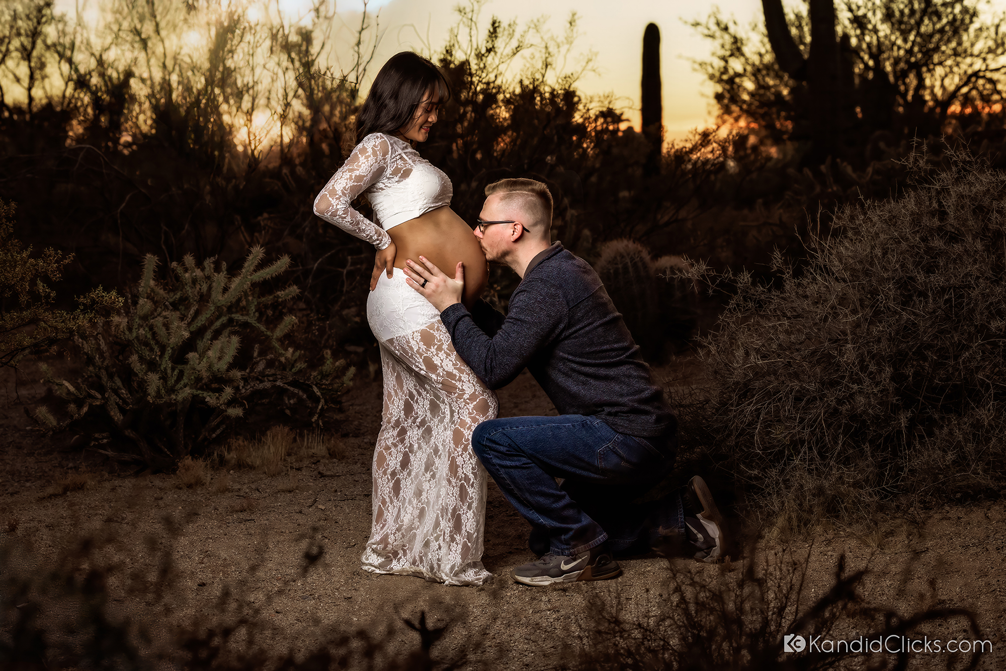Dad-to-be kisses pregnant belly during sunset maternity photoshoot in desert