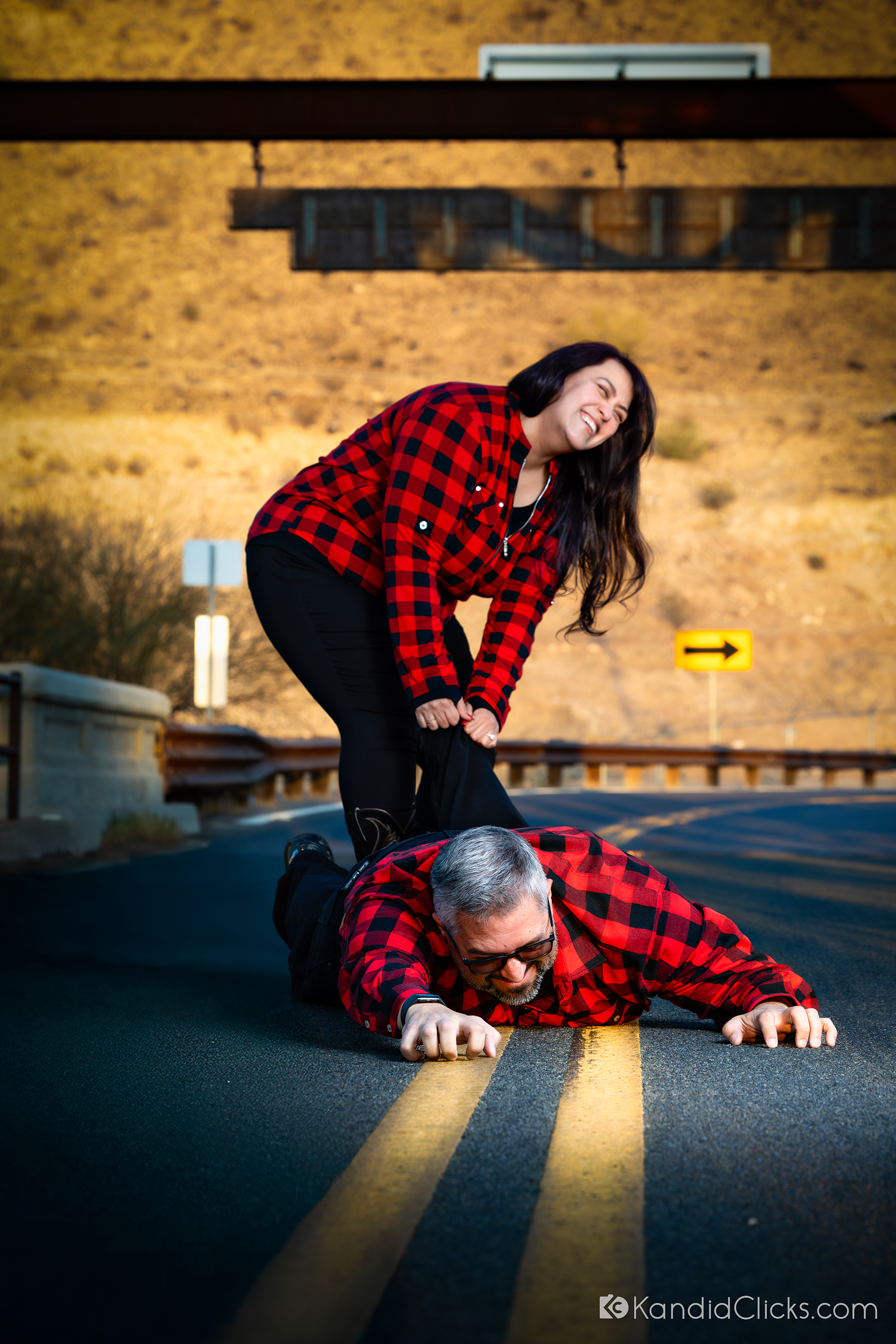 Couple in red plaid sharing a humorous engagement moment on a rural Arizona road.