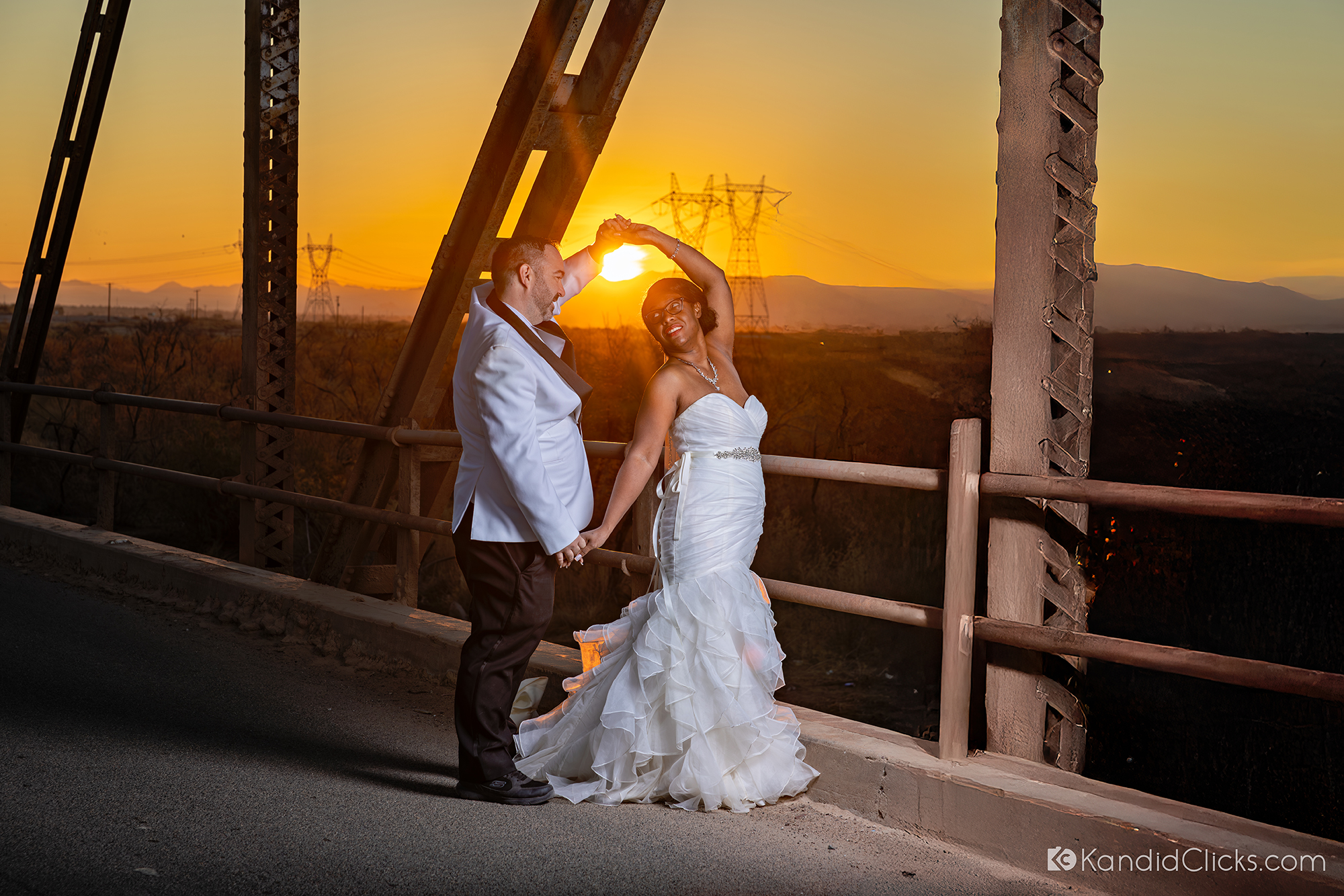 Bride and groom dancing at sunset on a rustic Arizona bridge.