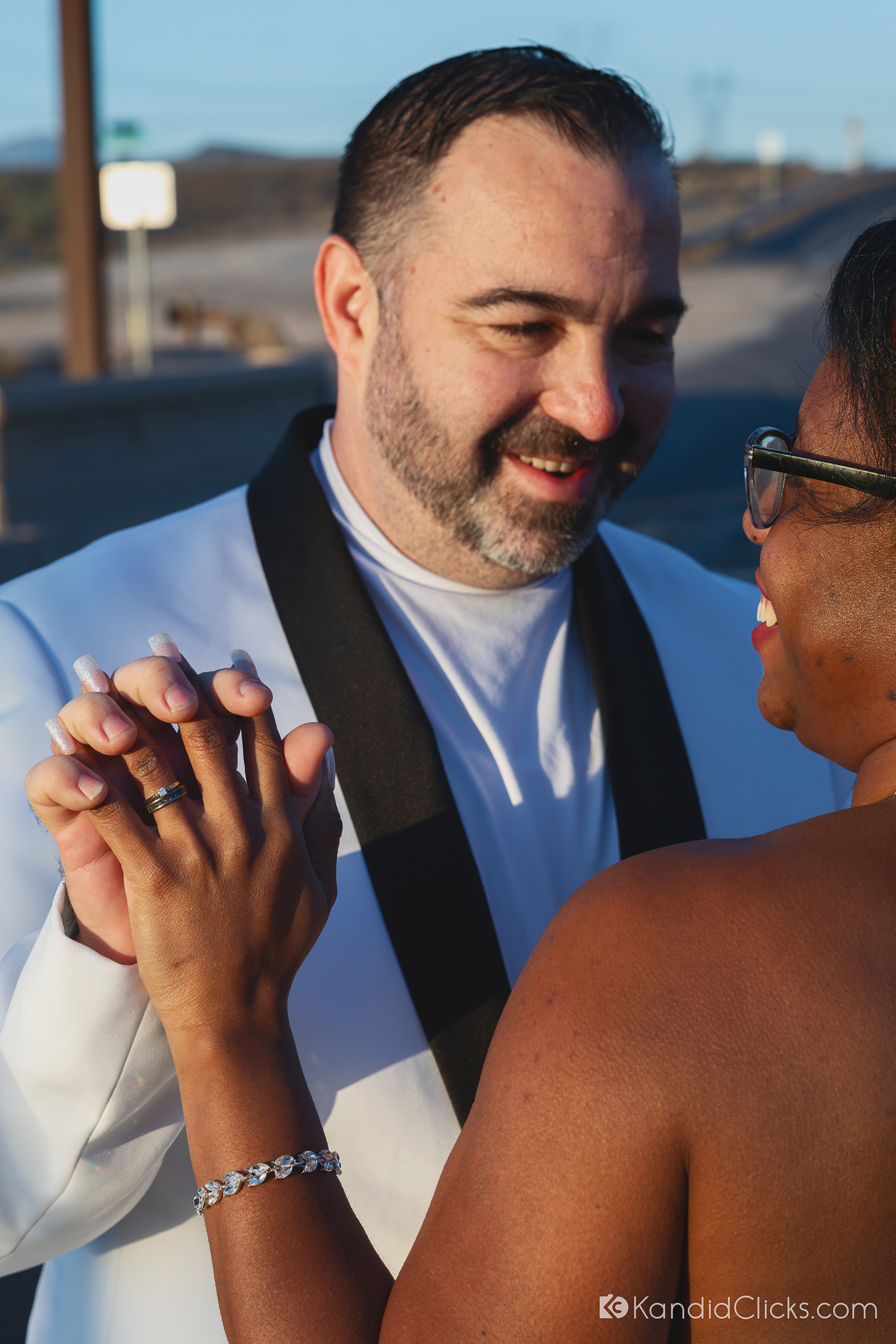 Close-up of groom smiling while holding bride’s hand during wedding moment.