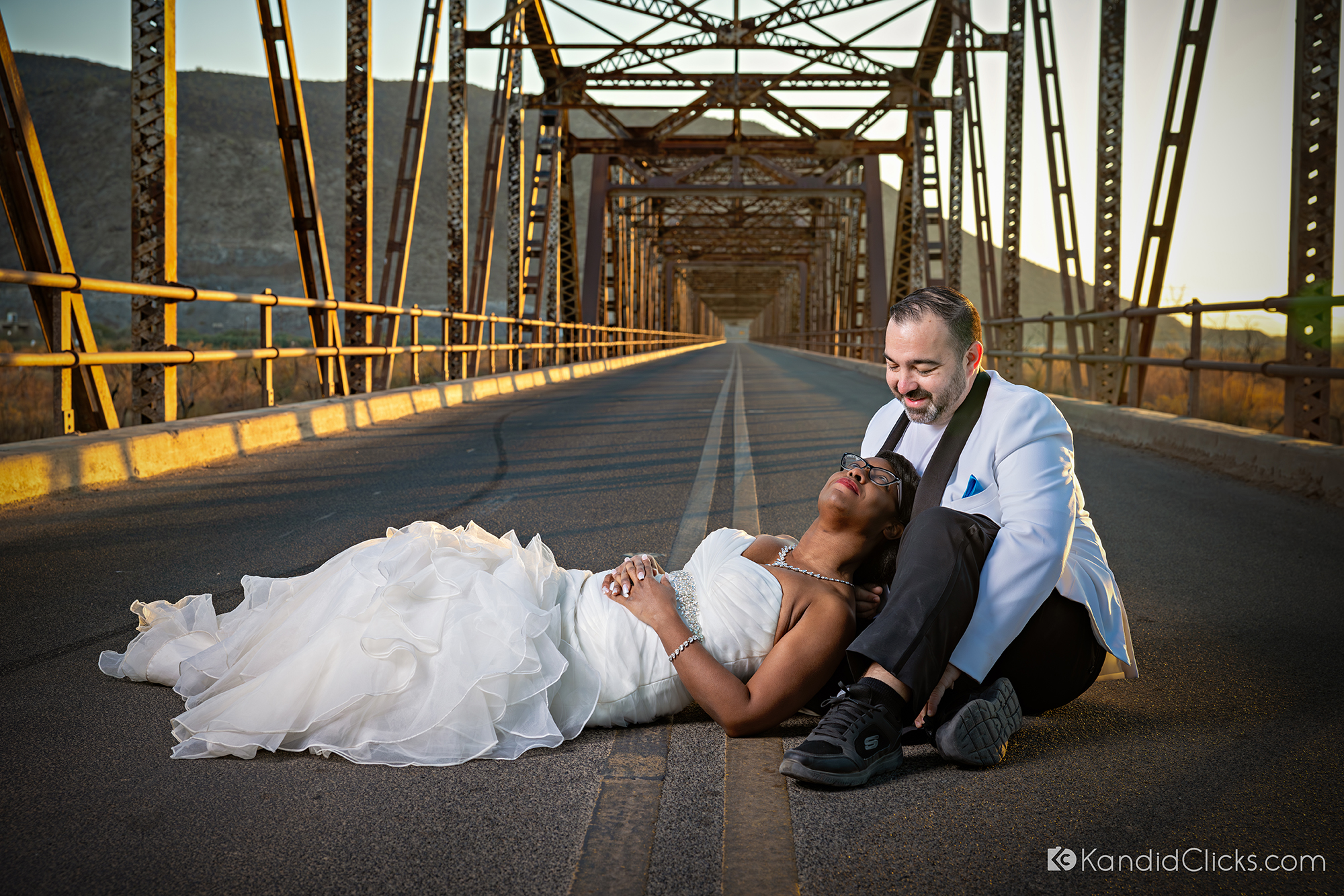 Bride laying in groom’s lap on a rustic bridge during their Arizona wedding.