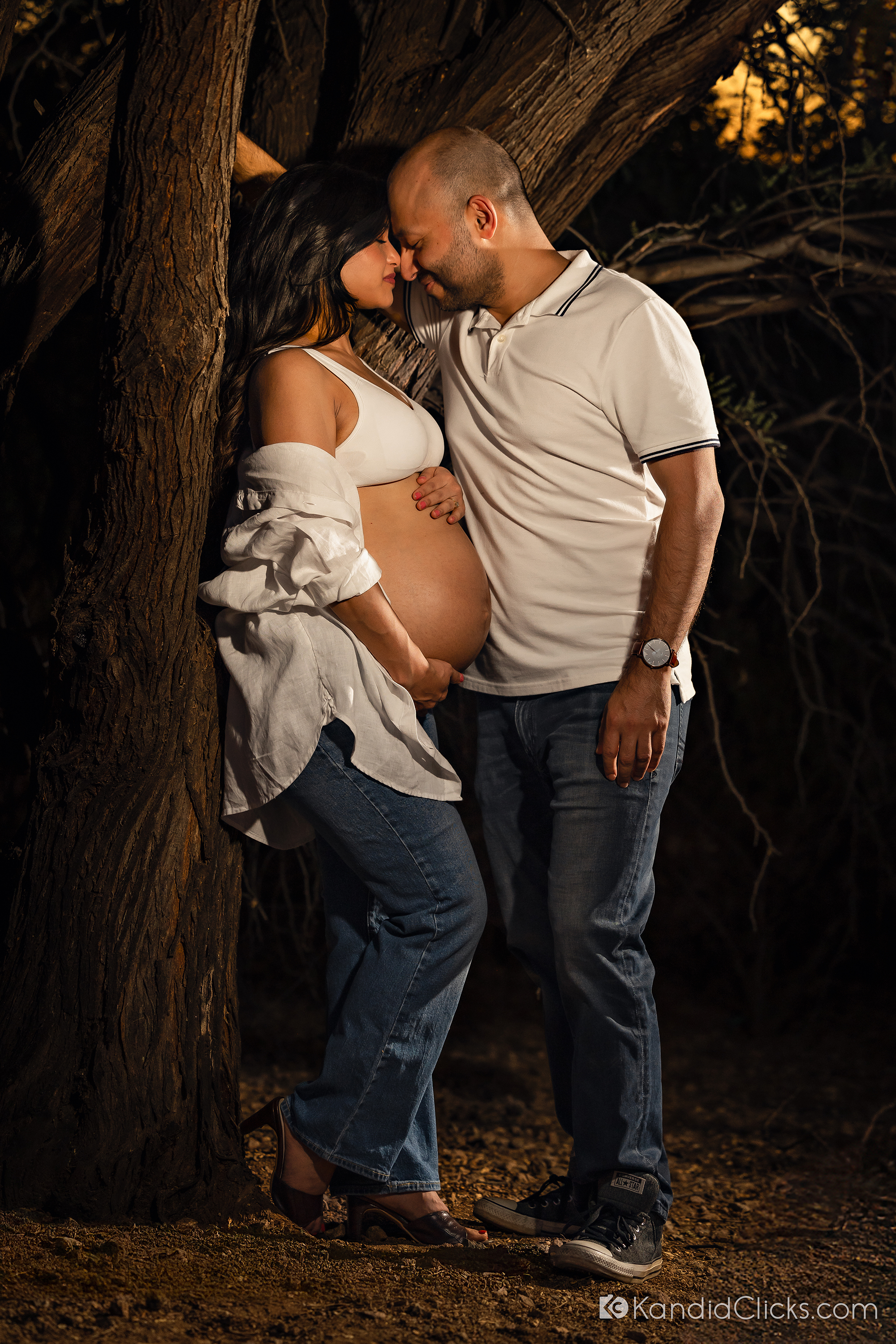 Maternity photographer captures quiet moment of love between expecting couple beside forest tree