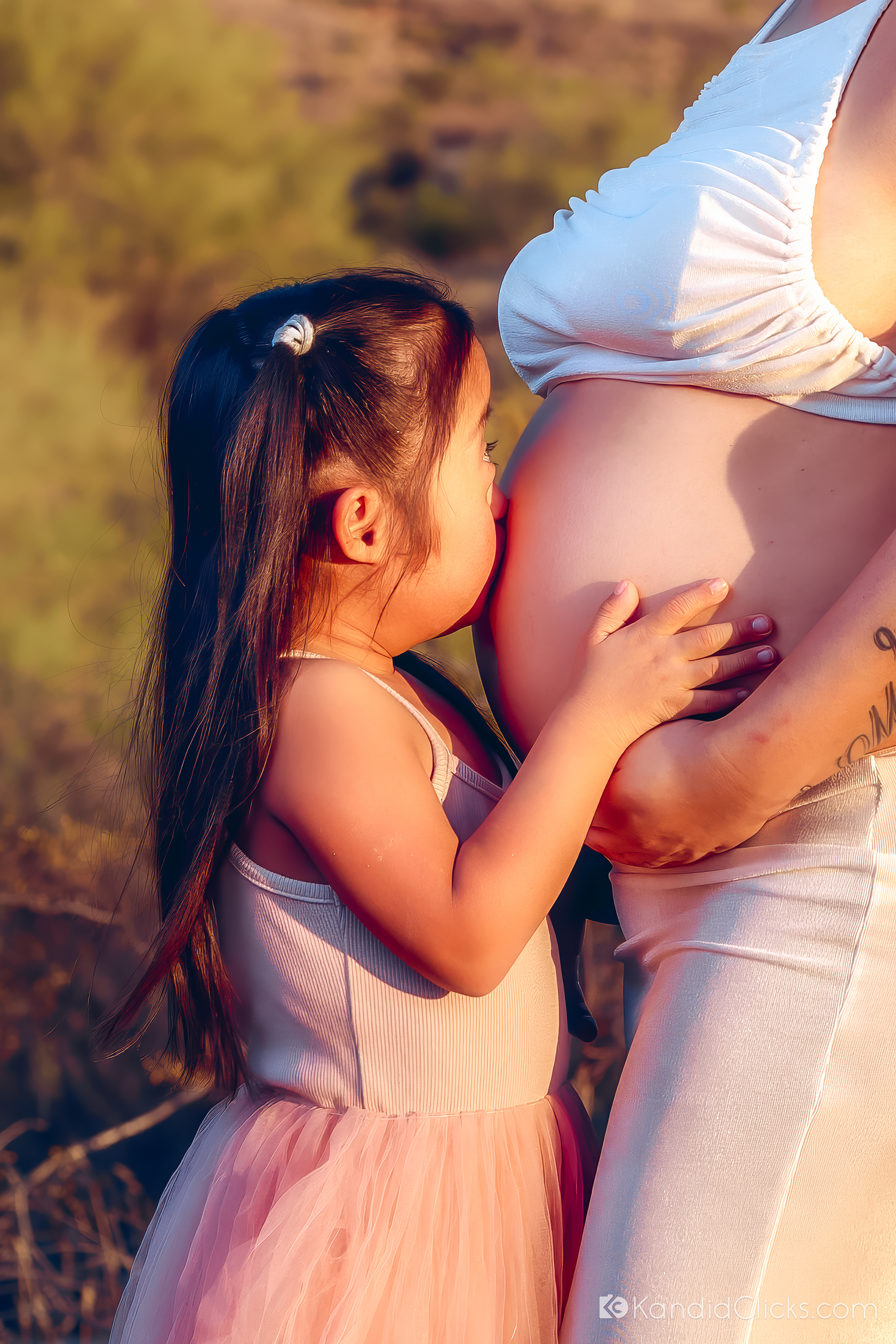 Maternity photographer captures sweet sibling moment as child gently kisses mother’s belly