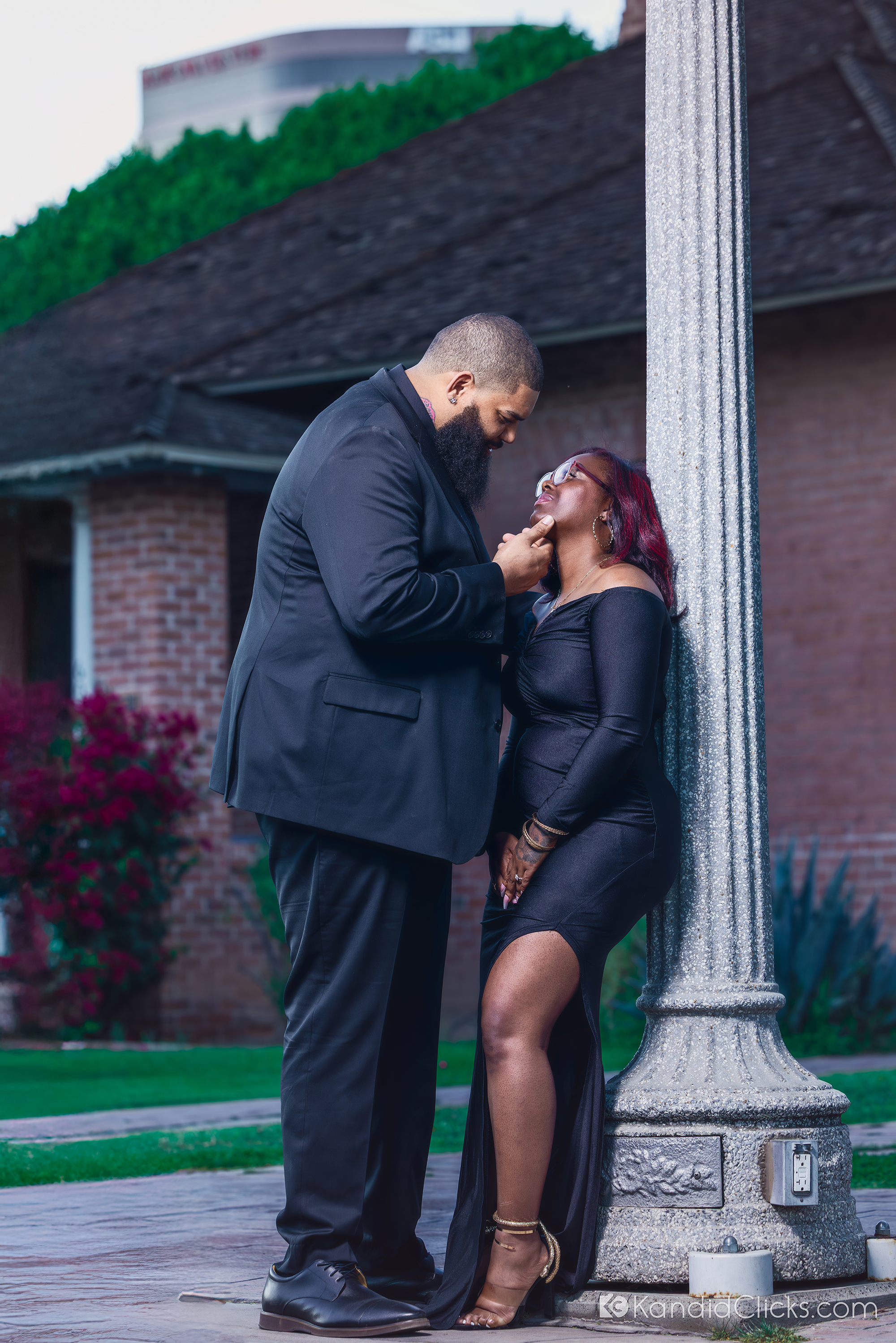 Stylish Black couple sharing an intimate moment near a vintage lamp post during their evening portrait session.