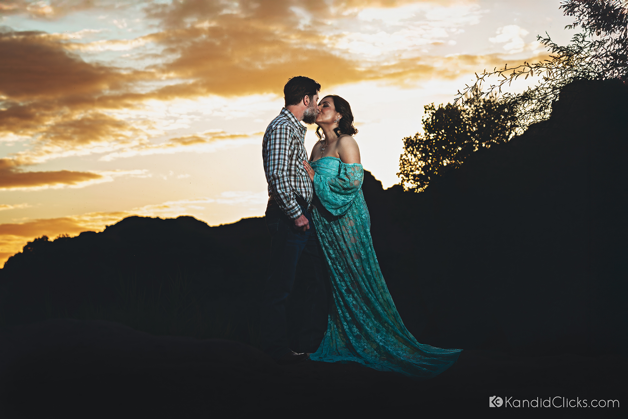 Pregnant couple sharing a kiss at sunset during an outdoor maternity photoshoot