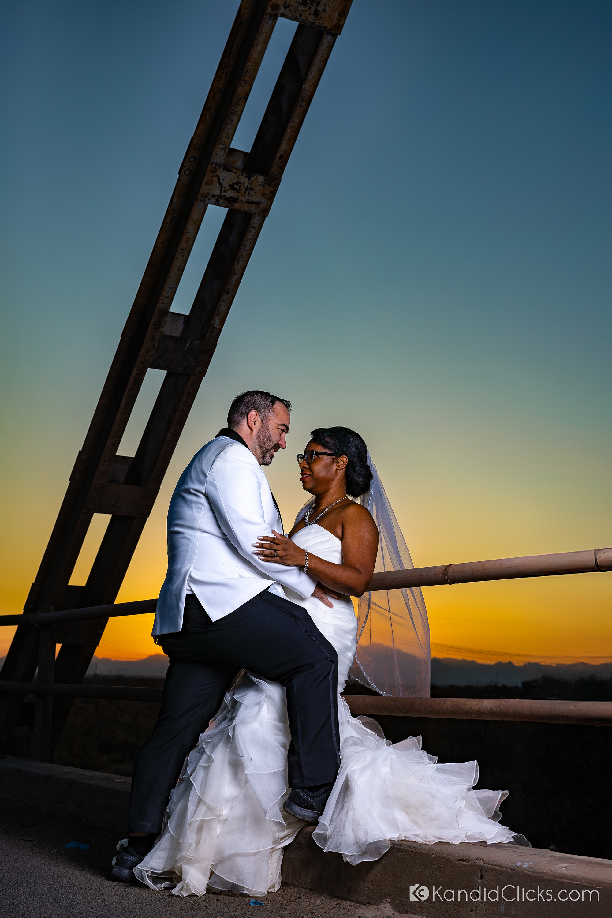 Bride and groom share an intimate moment during sunset on a rustic bridge.