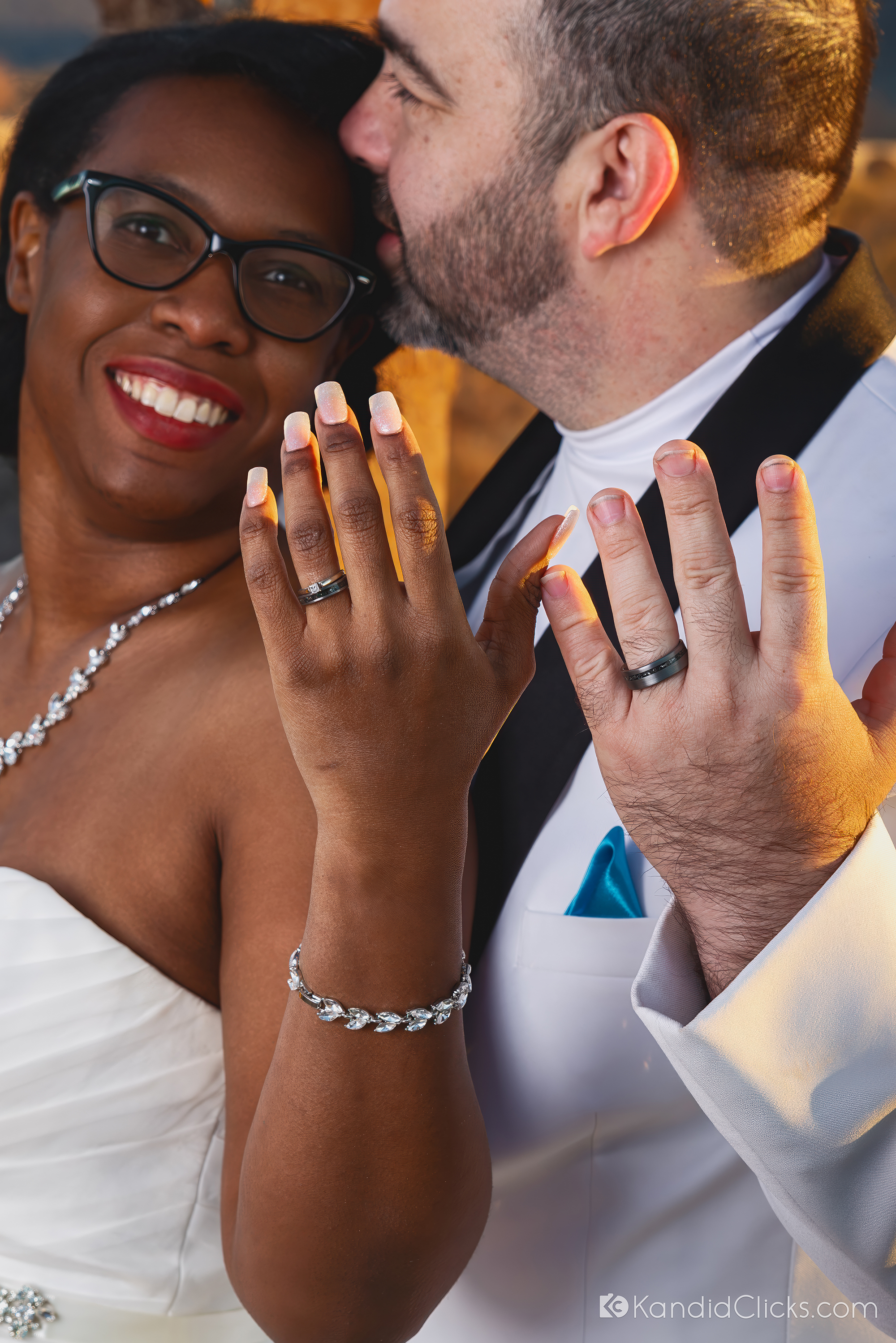 Bride and groom proudly showing wedding rings with joyful expressions.