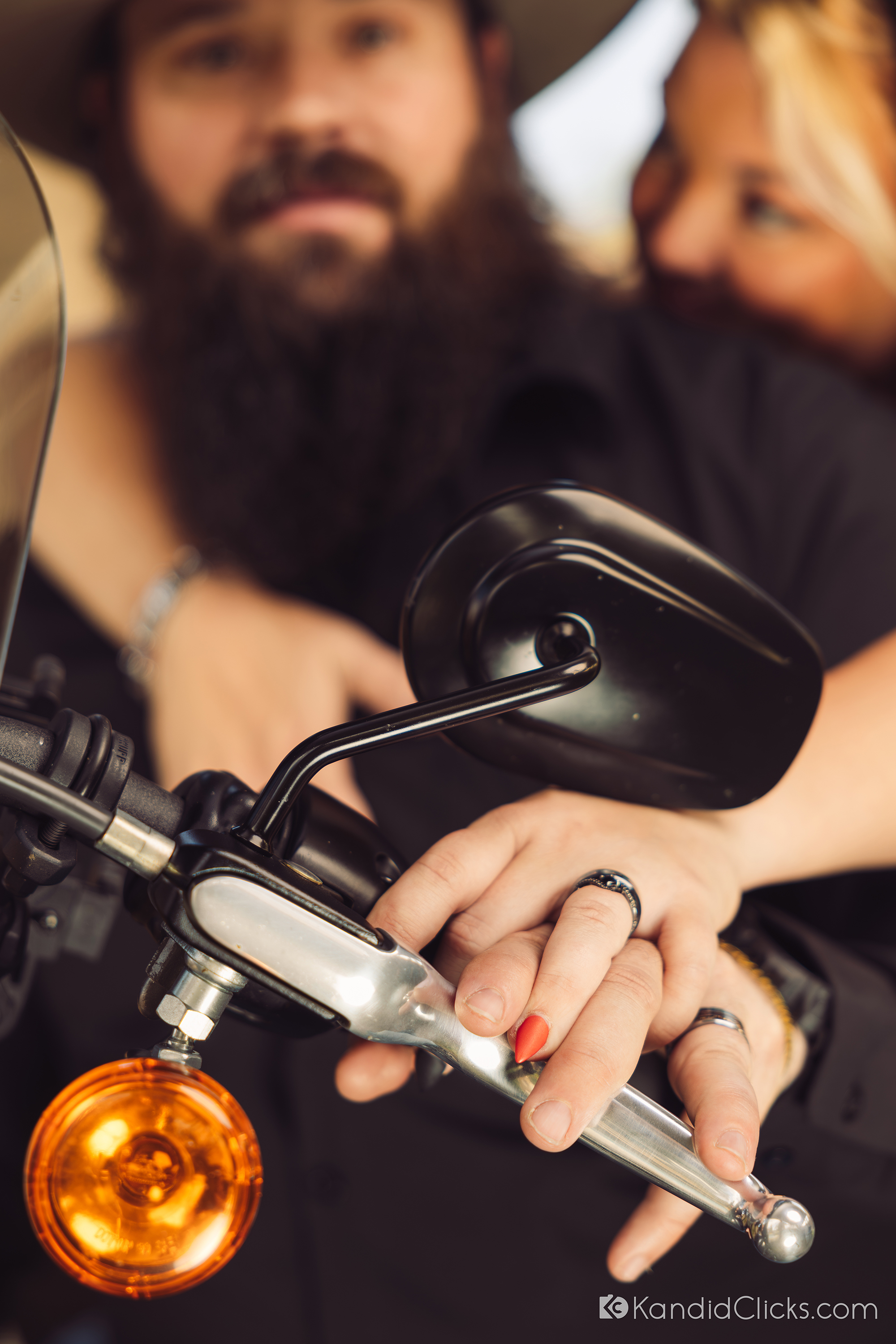 Bride and groom’s hands with rings resting on motorcycle handle in a close-up wedding shot.