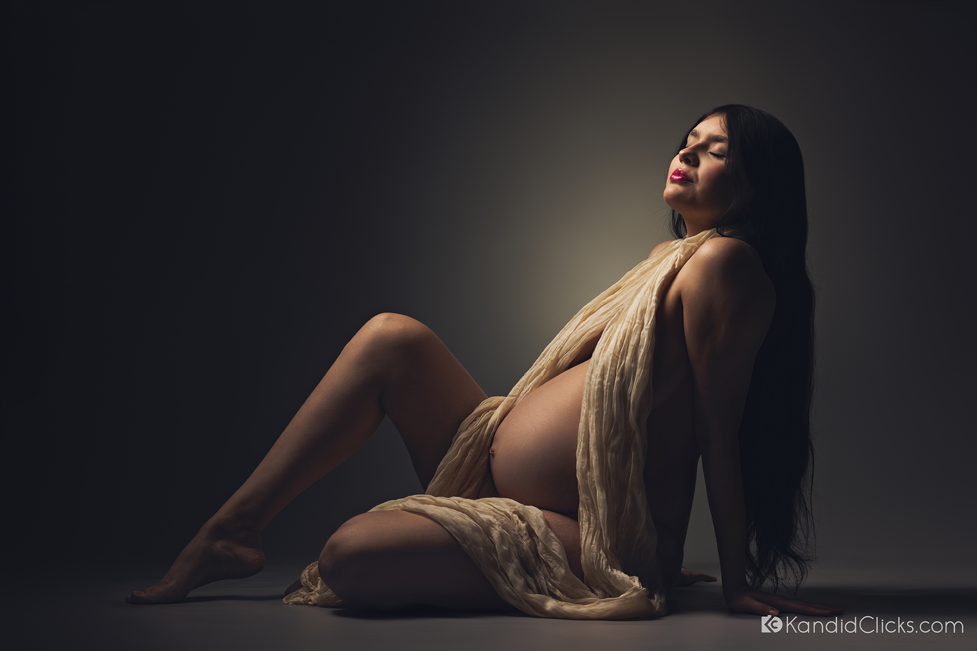 Pregnant woman in sheer wrap posing with closed eyes in fine-art maternity photography in Arizona.