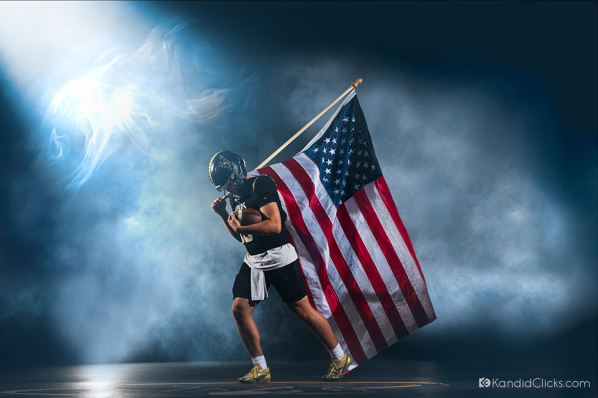 Football player holding American flag in dramatic lighting and smoke