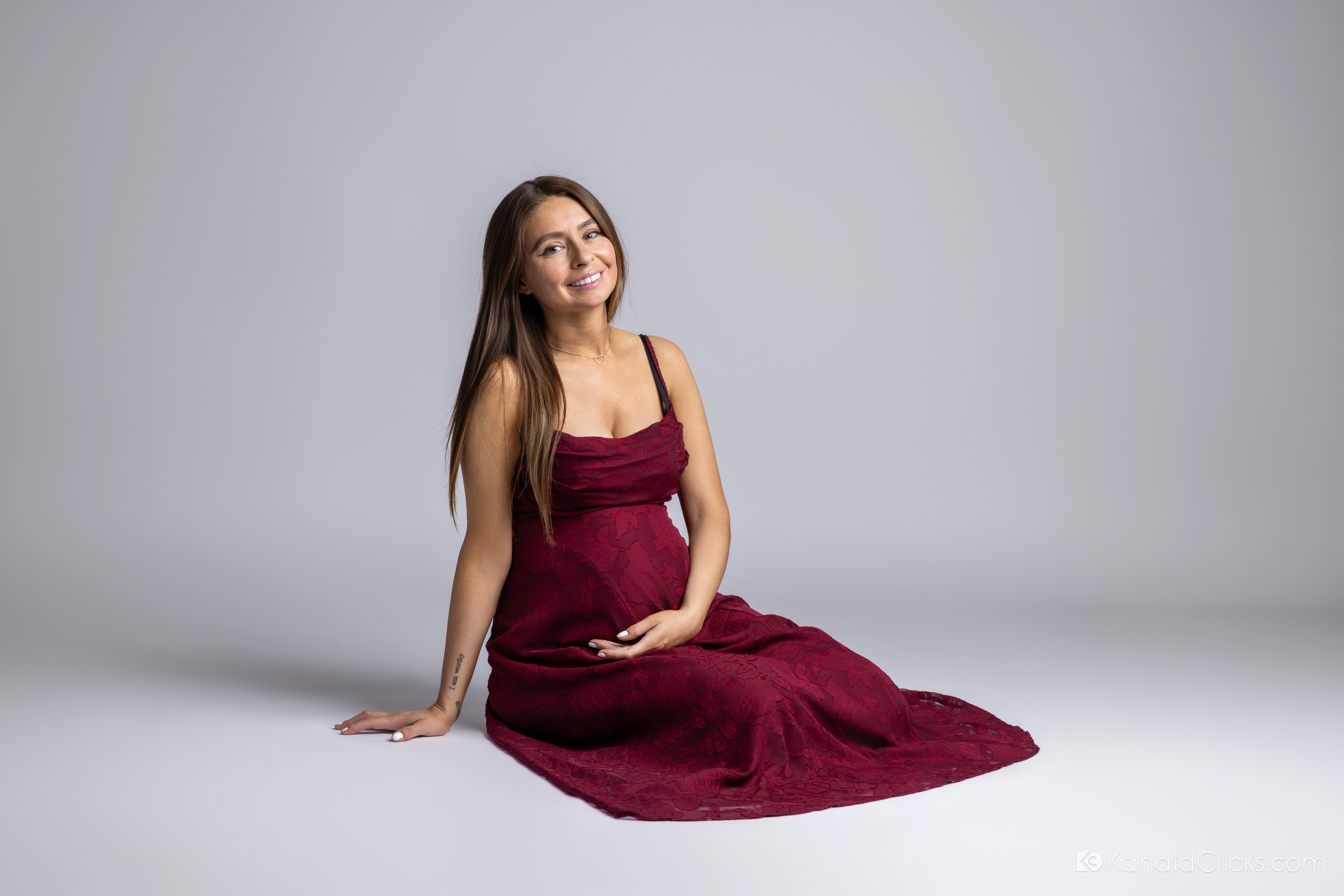 Soluna seated in a flowing burgundy gown at her Phoenix maternity session.
