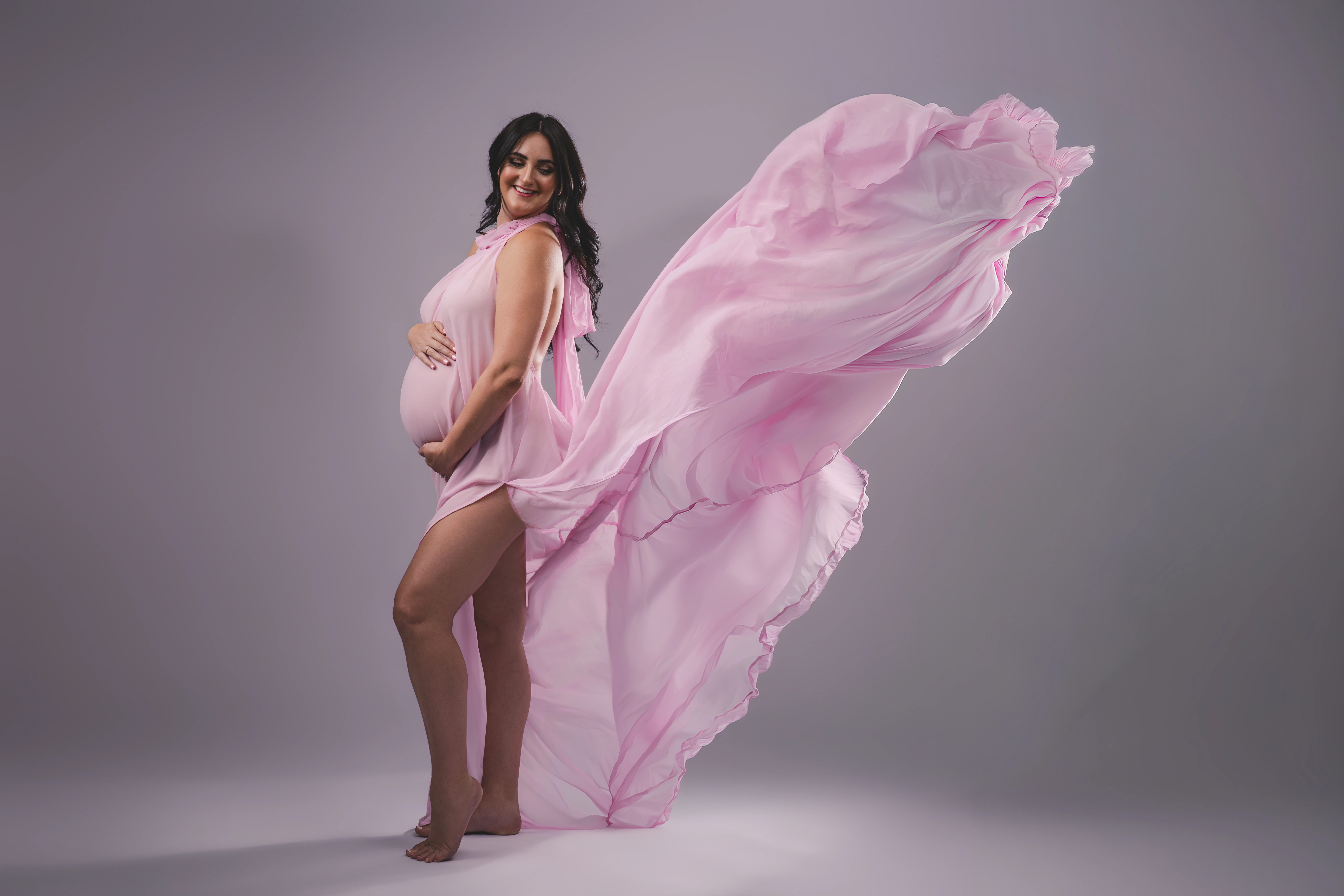 Krystina in a flowing pink maternity gown from the client wardrobe at her home studio session